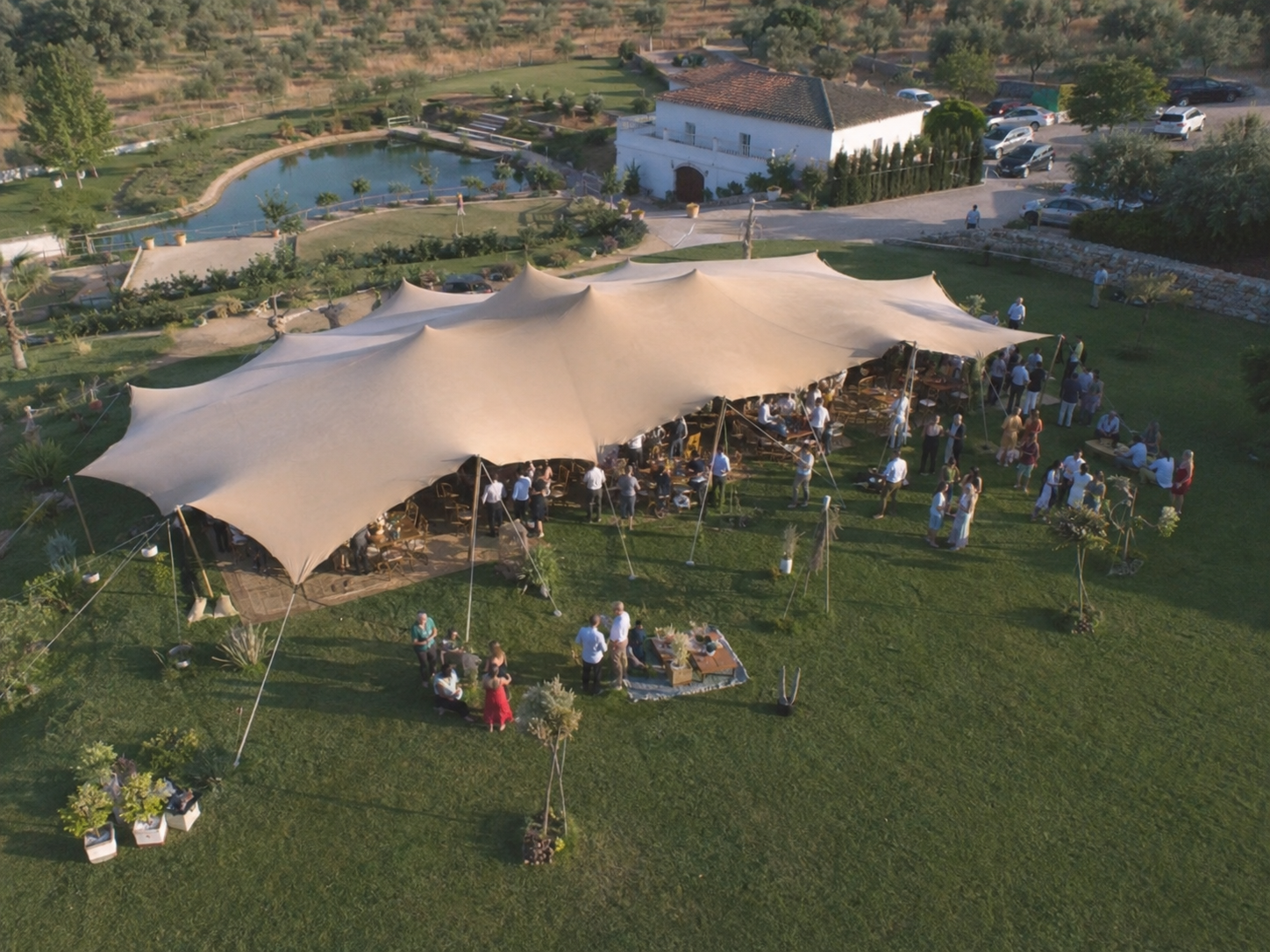 Carpa beduina tensada en finca con invitados, vista aérea