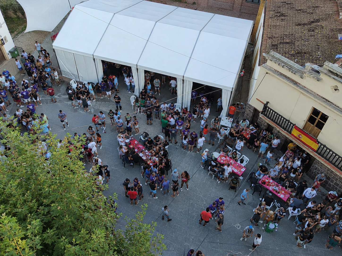 Vista aérea de una carpa modular blanca instalada en una plaza con gente disfrutando del evento